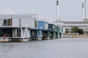 Viviendas construidas con contenedores marítimos apilados, con grandes ventanales y terrazas, junto al agua